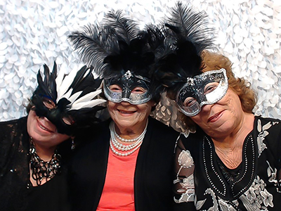 three older ladies pose with masks in the photobooth