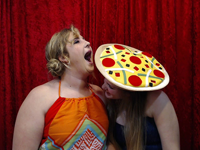 two girls playing with silly props in the picture booth